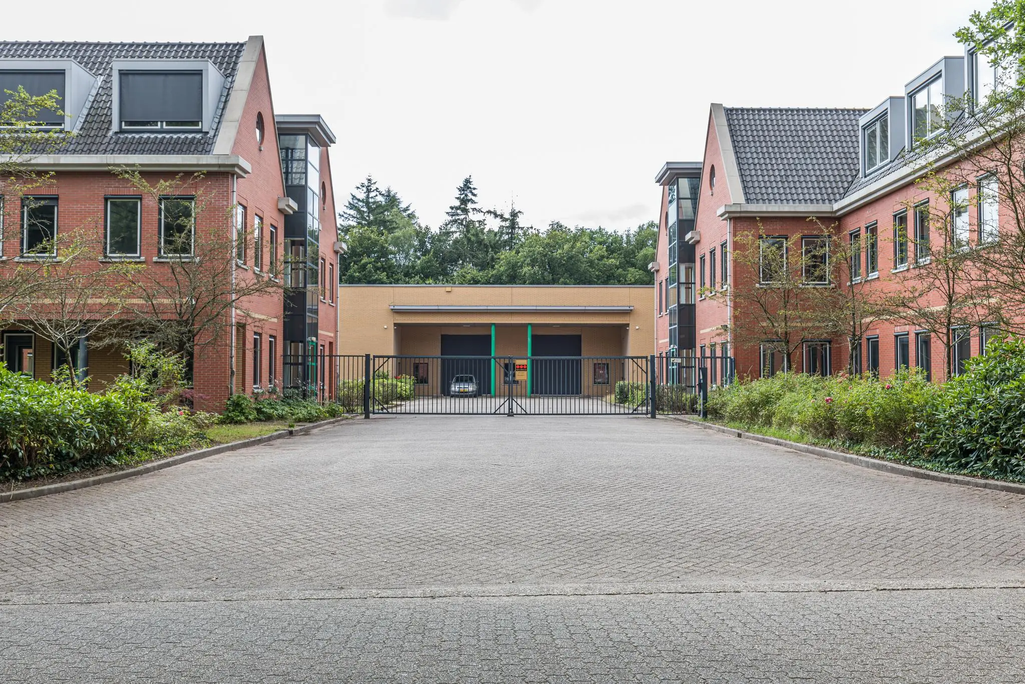 Twee rode kantoorgebouwen aan de Laan Blussé van Oud-Alblas met een gesloten toegangshek en een loods op de achtergrond.